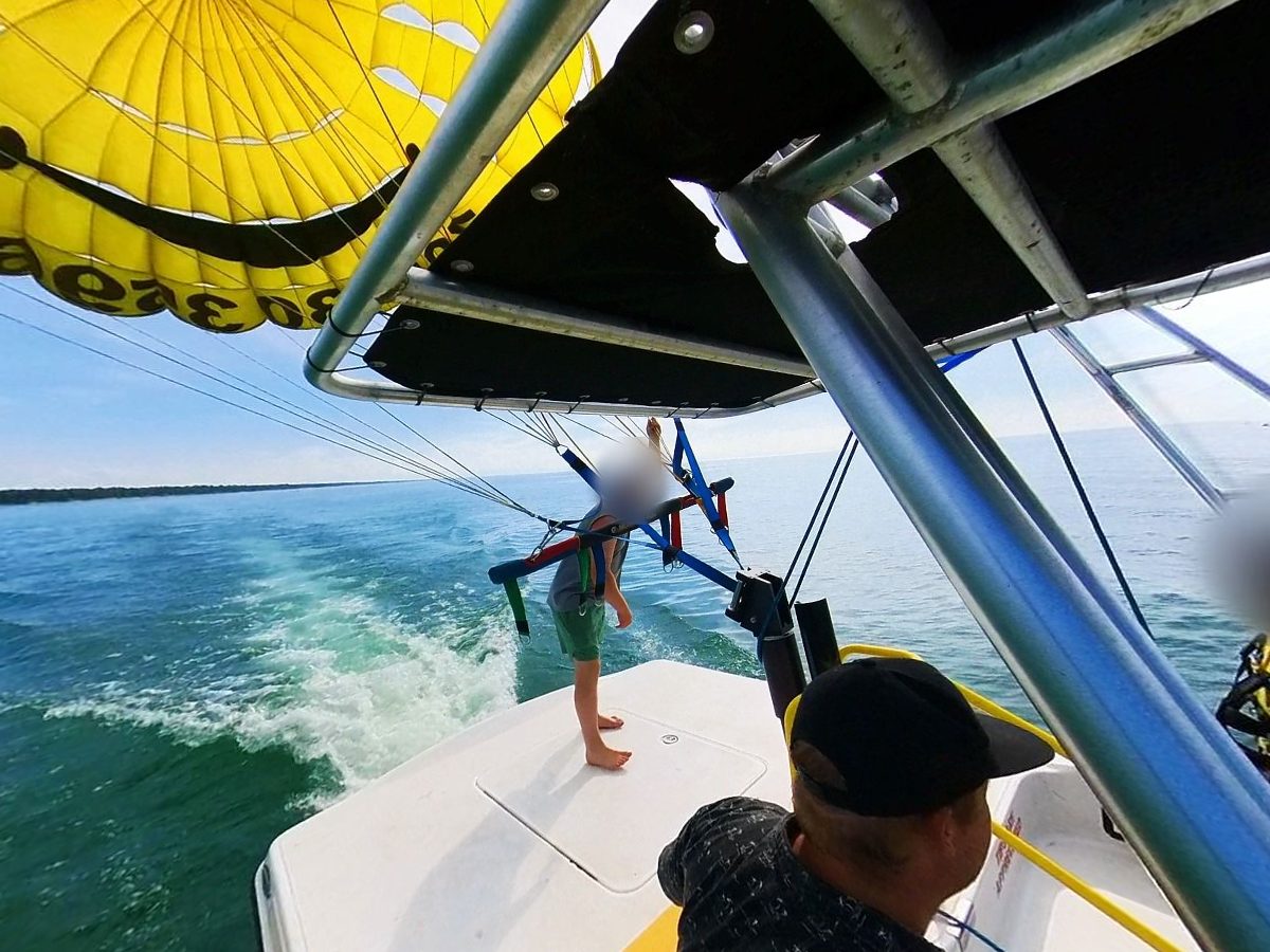Connor at the helm of the Grand Bend Parasail boat, a yellow smiley chute flying astern
